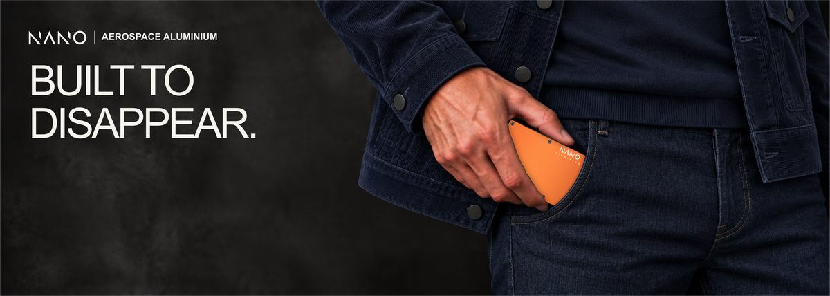 NANO Ventura Orange aerospace aluminium cash strap wallet — sliding into a trouser pocket