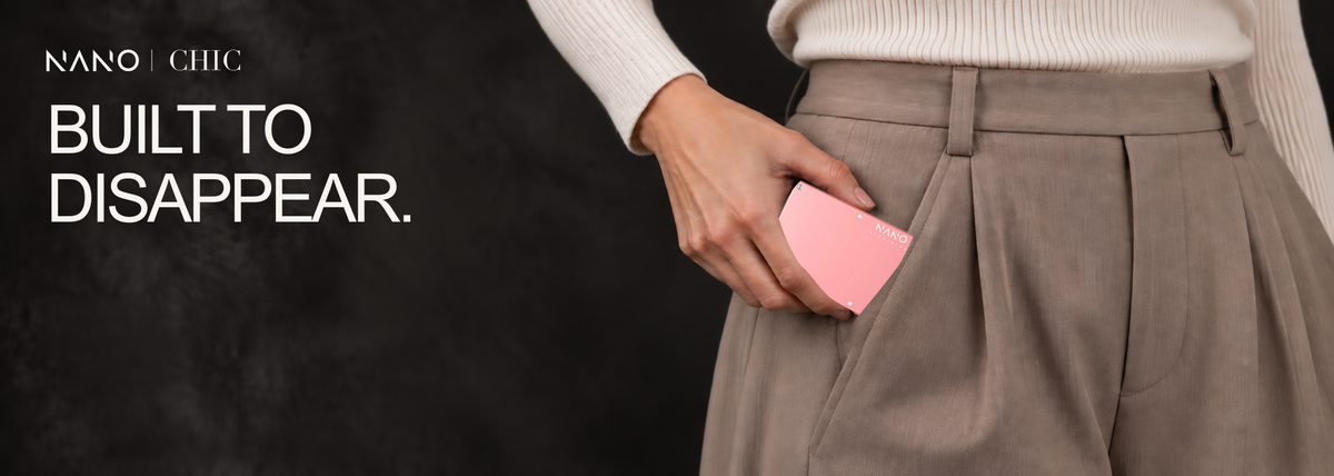 NANO CHIC — Built to disappear. Female model with blush-pink nails placing the Sunset Blush wallet into her trouser pocket. Desktop banner.