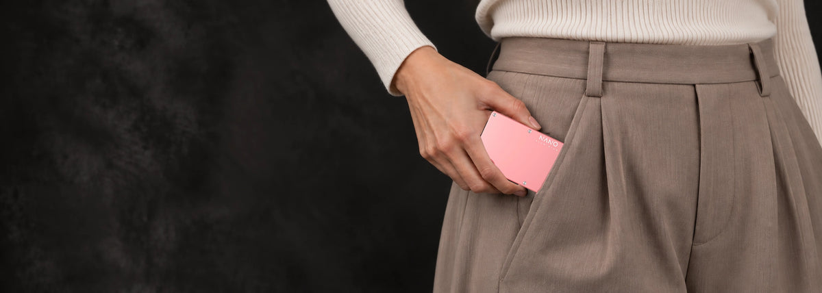 Sunset Blush NANO Chic wallet held at the pocket of pale taupe trousers.