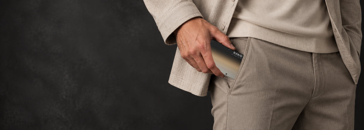 Onyx Eclipse wallet held in a taupe trouser pocket, with a stone overshirt and ecru knit.