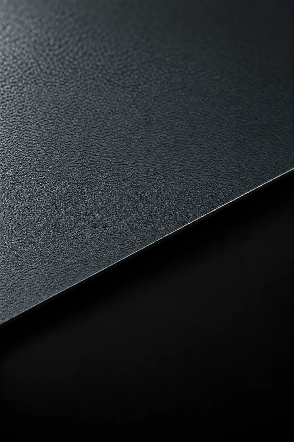 Powder-coated titanium material study with a textured blue-grey finish and a crisp diagonal edge.